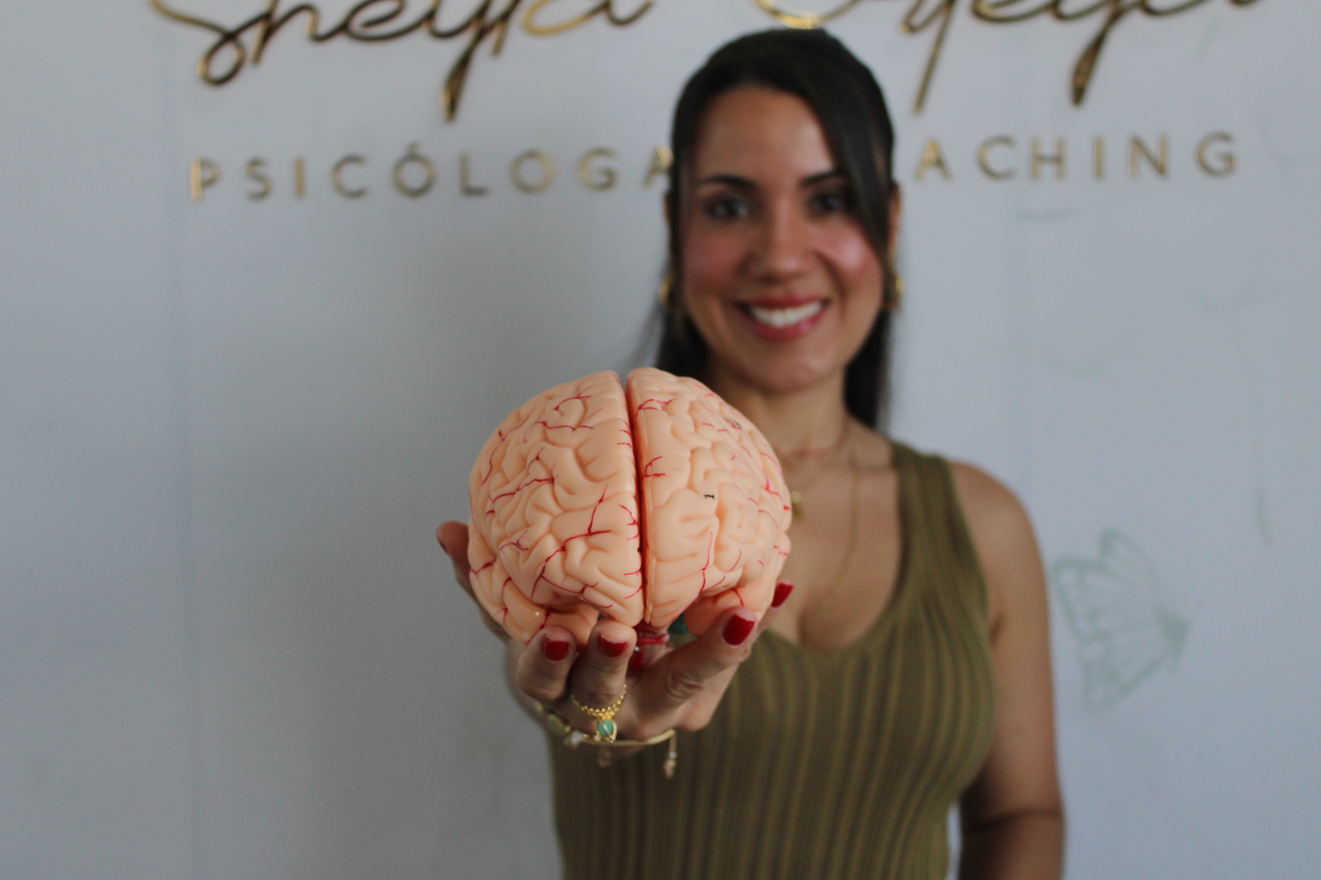 Sheyla Ortega sosteniendo un modelo anatómico de cerebro en su consultorio